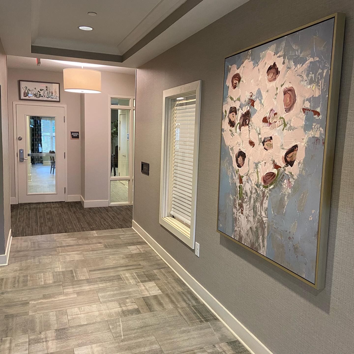 Finished hallway with wood-look flooring, gray walls and framed floral artwork