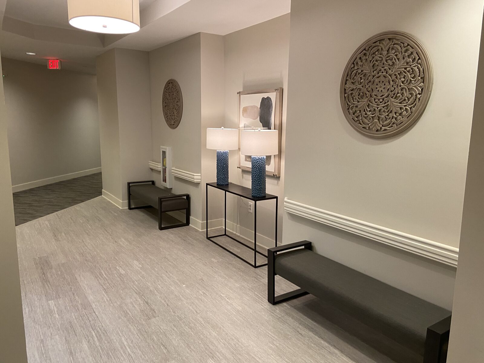 Building lobby with console table, lamps and bench on wood-look flooring