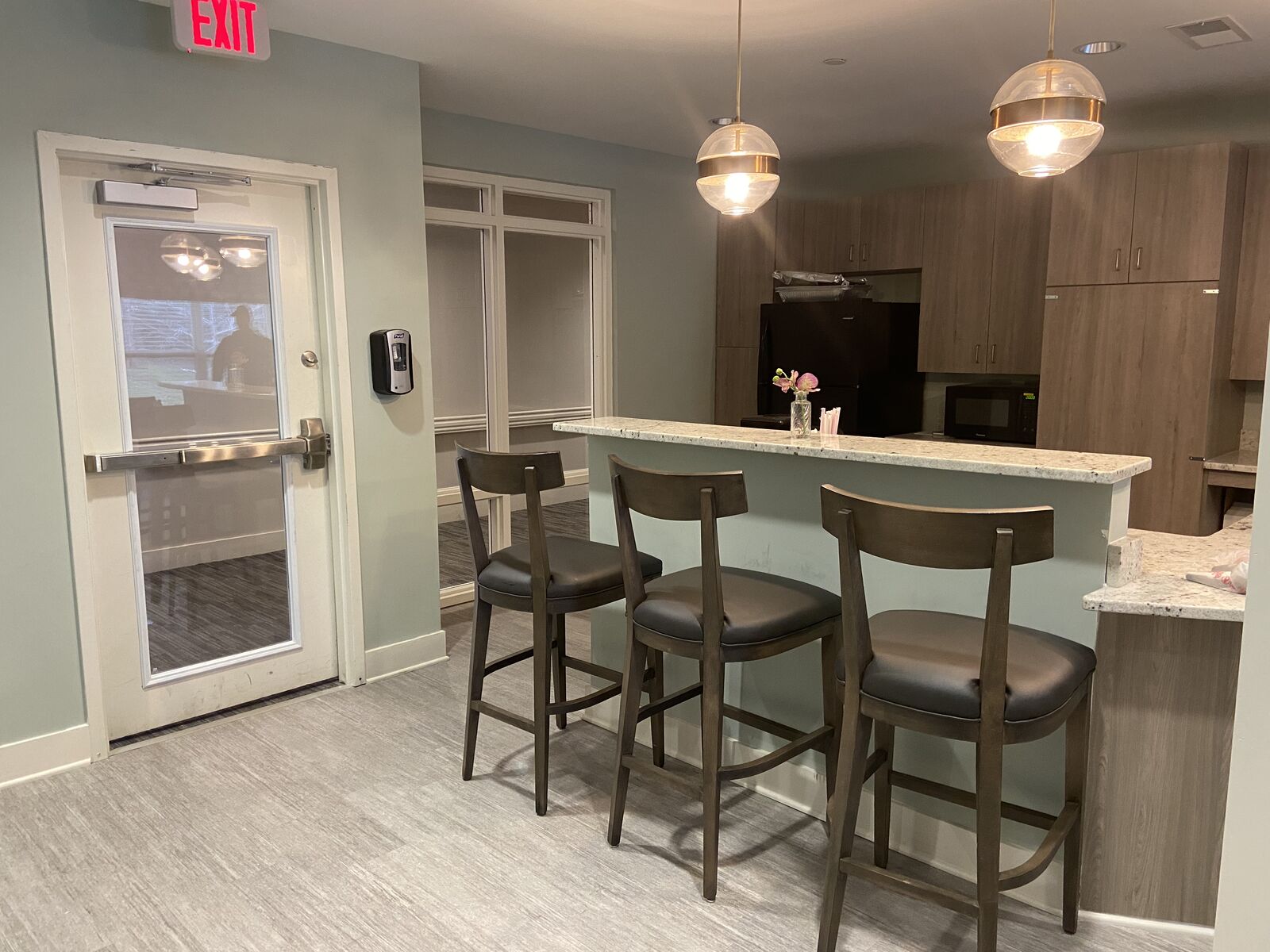 Community kitchen with bar stools, breakfast counter and pendant lights