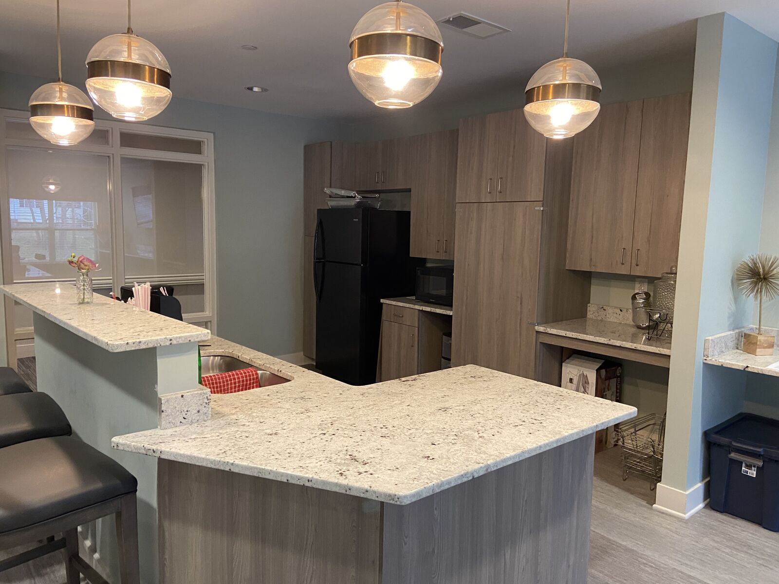 Community kitchen with stone countertop island and globe pendant lights