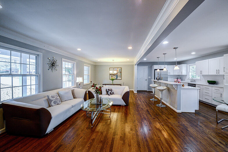 Open-concept living room with hardwood floors and white kitchen