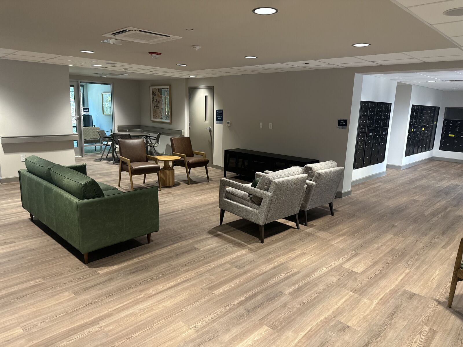 Open resident lounge with green sofa and armchairs on wood-look flooring