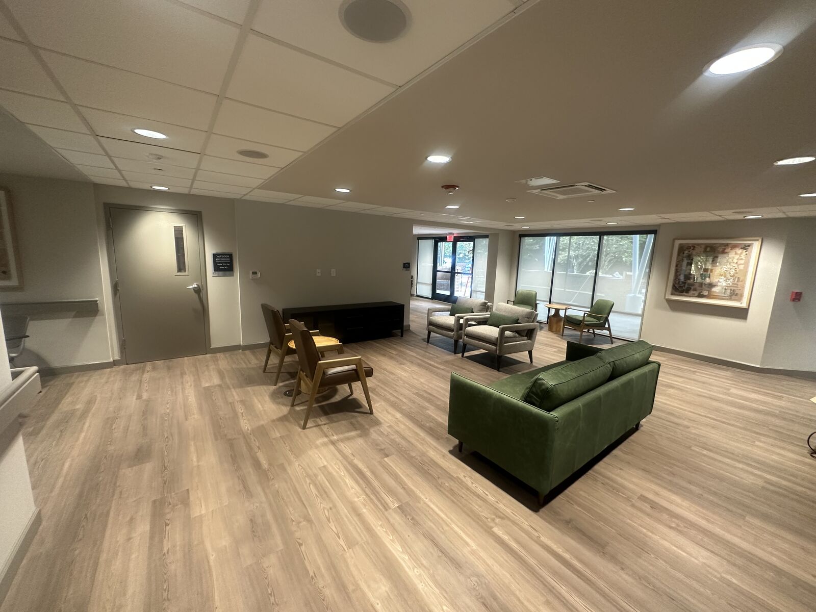 Resident lounge with green sofa, side chairs and large windows