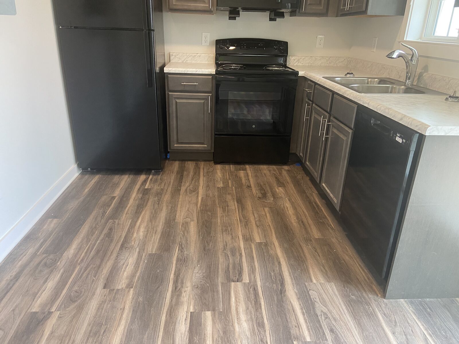 Galley kitchen with black range, refrigerator and wood-look flooring