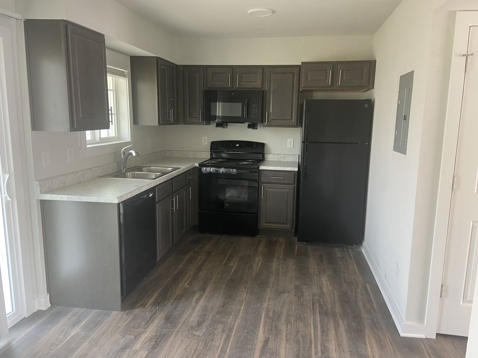 Renovated apartment kitchen with dark cabinets and black appliances