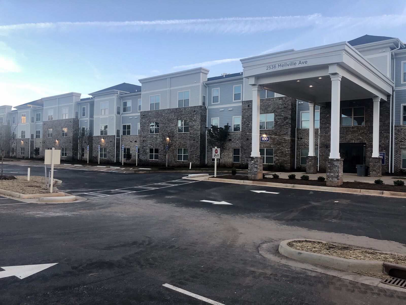 Apartment community exterior with columned entry portico and parking lot