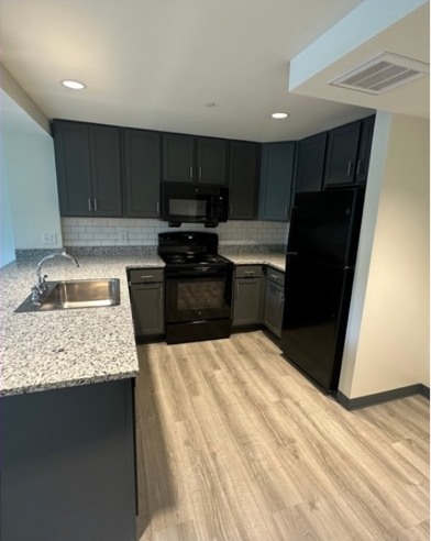 Renovated kitchen with dark cabinets and wood-look flooring